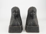 pair of black stone sphinx statues of a woman and a man