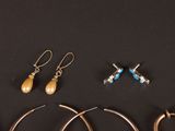 several pairs of earrings and a pair of scissors on a black surface