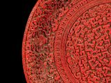 a red plate with a design on it on a black background