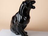 a black statue of a cat sitting on a white surface