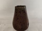 a brown vase sitting on a clear shelf on a table