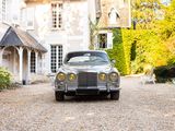a silver car parked in front of a large house