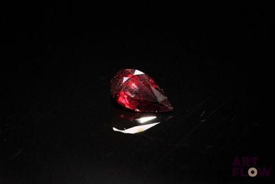 a close up of a red diamond sitting on top of a black surface