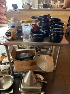 de nombreuses casseroles et poêles posées sur une table dans la cuisine