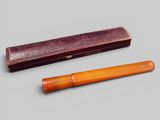 deux stylos en bois et un étui en cuir posés sur une surface grise