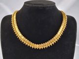 un collier en or sur un mannequin sur fond blanc