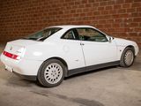 a white car that is parked in front of a brick wall