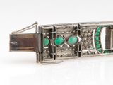 an image of a silver bracelet with green stones on a white surface