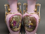 une paire de vases roses et dorés ornés d'une peinture représentant un homme et une femme