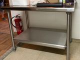 une table en acier inoxydable dans une cuisine équipée d'un extincteur