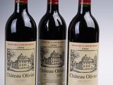 three bottles of red wine are lined up on a white surface