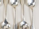 six silver spoons are lined up in a row on a white surface