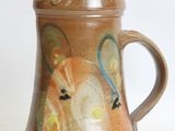 a brown pitcher with a horse on it on a white surface