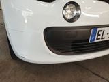 the front end of a white car with a number plate on it