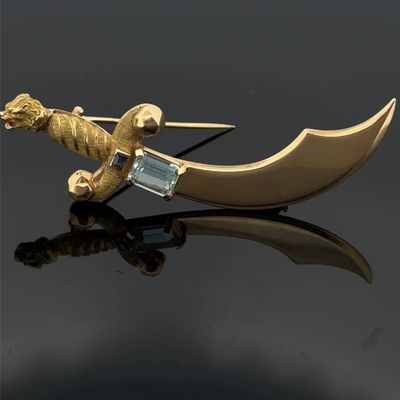 a gold brooch with a dragon and a sword on it