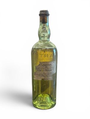 an old bottle of liquor sitting on top of a white surface