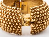a close up of a gold bracelet on a white surface