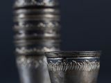 a silver shot glass sitting next to a stack of silver cups