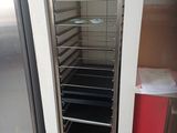 un réfrigérateur ouvert dans une cuisine où se trouve une poubelle rouge