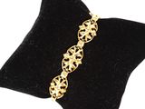 un gros plan d'un bracelet en or posé sur un coussin en velours noir