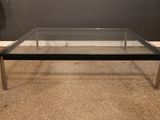 une photo d'une table basse en verre posée sur un sol recouvert de moquette