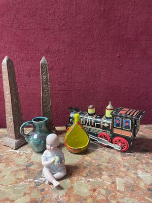 a small statue of a baby sitting on a table next to a toy train