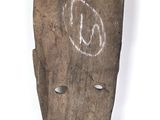 un vieux masque en bois sur lequel figurent des inscriptions blanches sur un fond blanc