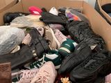 plusieurs paires de chaussures dans une boîte posée sur le sol