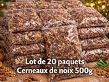 un tas de noix et de fruits à coque posés sur une table, avec un sapin de Noël en arrière-plan
