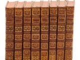 six vieux livres alignés sur une surface blanche