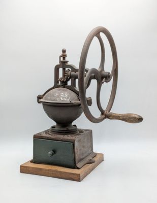 an old coffee grinder sitting on top of a wooden base