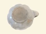 a white tea pot with a brown rim on a white surface