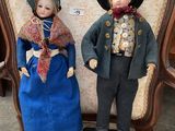 pair of antique dolls of a boy and a girl sitting on a chair