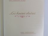 an open book on a white surface with pink writing on it