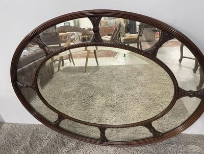 a large oval mirror sitting on the floor in a living room