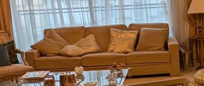 un salon avec un canapé, un fauteuil, une table basse et une lampe