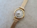 a gold wrist watch with a white face on a table