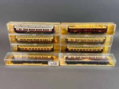 quatre trains miniatures dans des boîtes en plastique posés sur une surface grise