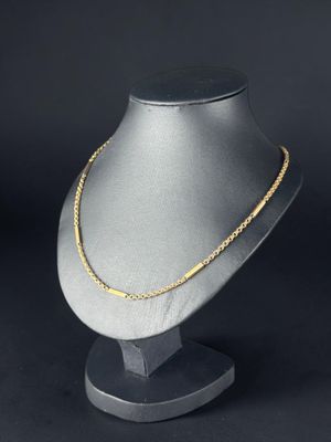 un collier à chaîne en or posé sur un présentoir pour mannequin