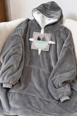 une couverture posée sur un canapé, avec un sweat à capuche posé dessus