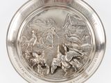 une image représentant une assiette en argent sur laquelle figurent une femme et des oiseaux