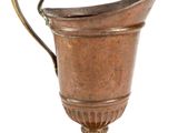 an antique copper pitcher with a curved handle on a white background