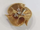 a close up of a gold brooch with diamonds on a white surface