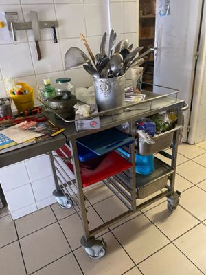chariot de cuisine en acier inoxydable sur lequel sont posés des ustensiles, dans une cuisine