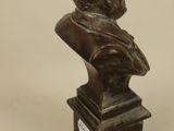 bronze bust of a man with a hat on top of a wooden base