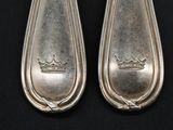 pair of silverware spoons with a crown on each of them