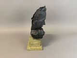 a black sculpture of a head on a wooden base