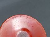 someone is holding a red frisbee with a white spot on it