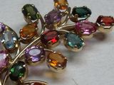 une image représentant une broche ornée de pierres multicolores sur un fond blanc
