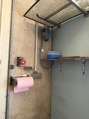 une salle de bains équipée de toilettes et d'une étagère sur laquelle est posé un rouleau de papier toilette